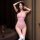 A woman poses confidently wearing a sheer pink bodysuit with an open crotch design, paired with white thigh-high socks. the s...