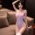 Woman wearing lavender japanese-style sexy bodysuit swimwear with open-crotch design, posing on a beige sofa.