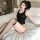 Woman modeling black japanese-style sexy deadstock swimsuit bodysuit with open-crotch design, posed seductively on white bed ...