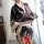 A woman wears a black japanese-style kimono with vibrant floral patterns, holding a traditional folding fan. the design featu...
