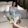 Woman wearing light blue floral japanese-style sleepwear set with kimono bathrobe, bow waist tie, and matching shorts, holdin...