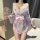 Woman wearing pink floral japanese-style sleepwear set with bow, holding a decorative fan.