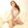 A woman poses on a fluffy white rug wearing a sheer mesh bodysuit, featuring a school uniform-inspired design. the outfit hig...
