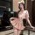 Woman wearing pink jinxiao jk flirty lingerie skirt with pleated design, lace eye mask, and fluffy ears in elegant indoor set...