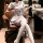 A woman sits confidently in an office chair wearing a white sailor-style jk uniform set, featuring blue accents and thigh-hig...
