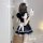 A woman wearing a black and white maid dress with puffy sleeves and a bow, taking a selfie in a room. the outfit features ruf...