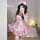 A woman wearing a pink maid dress with ruffles and bows, perfect for cosplay or anime-themed events.