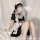 A woman wearing a black and white maid outfit with adjustable straps, sitting provocatively with steam coming from her mouth.