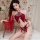 Woman wearing red kouni hanfu lingerie set with floral embroidery, tassels, and sheer sleeves on a bed.