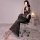 A woman poses in a black sheer lace bodycon dress, featuring delicate lace details and a plunging neckline. the see-through f...