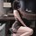 Woman wearing kouni sheer backless lingerie set with strappy design, posing in a modern bedroom setting.