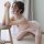 A woman poses elegantly in a sheer pink lace babydoll sleep dress, exuding romance and femininity with delicate pearl accesso...