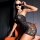 Woman wearing a black lace bodysuit dress, sheer bodycon nightdress with thong, posing on an orange chair.