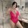 Woman wearing a hot pink lace bodysuit with open-crotch design in a modern bathroom.