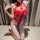 Woman wearing red lace bodysuit with cheongsam-style top and open-crotch design, posing on bed in sexy sleepwear.