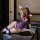 Woman wearing purple lace bodysuit set with sheer cut-out bra and panty, paired with fishnet stockings, posing seductively on...