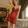 Woman wearing red lace chemise sleepwear set, sheer lingerie pajamas with floral details, elegant bedroom setting.