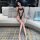 Woman wearing black lace cut-out bodysuit with sheer mesh stockings, seated on a modern sofa in a stylish room.