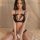 Woman wearing black lace lingerie set with pearl embellishments, featuring a bralette and thong for small bust.