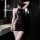 Woman wearing black lace halter neck bodysuit with sheer mesh panels and cutout sides, styled as a seductive bodycon sleep dr...