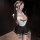 Woman wearing white lace jk-style lingerie set with sheer peek-a-boo top, black mini skirt, bow detail, and blindfold.