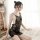 Woman wearing black lace mesh babydoll sleep set with sheer floral embroidery, posing on a fluffy rug in a bright room.