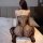 Woman wearing lace mesh bodysuit sleepwear with fishnet stockings, back view on bed.