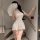 Woman in white lace mesh cheongsam lingerie with sheer vintage design, tied front, and bare-butt cutout, holding a fan on sta...