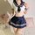 A woman models a lace mesh jk costume set featuring a sailor-style top with a navy mini skirt, sheer tights, and a stylish bo...