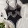 Black lace mesh bodysuit with floral detailing, displayed on white silk with roses and accessories.