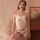 Woman wearing white lace bodysuit set with open-crotch design, pearl necklace, and earrings in soft bedroom setting.
