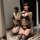 Woman kneeling in black lace see-through bikini set with matching mask, posing seductively in front of mirror.