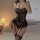 Woman wearing black lace bodysuit with sheer mesh corset top, adjustable straps, and garter belt style in bedroom setting.