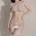 Woman wearing a delicate white lace lingerie set with sheer bralette, matching thong, and garter stockings.