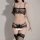 Woman modeling black lace sheer lingerie set with see-through bralette, thong, and garter stockings for seductive allure.