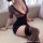 Woman wearing a black lace sheer bodycon mini dress with deep v neckline and floral mesh sleeves, paired with thigh-high stoc...