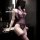 Woman wearing purple lace sheer bodysuit in bathroom setting, featuring mesh transparent lingerie design with floral details ...