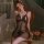Woman wearing black lace sleepwear set, sheer lingerie outfit with floral details, seated on vintage chair in romantic bedroo...