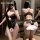 Woman modeling black lace temptation open-crotch bodysuit, sheer lingerie with lace detailing and bow back.