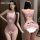 Woman modeling pink lace open-crotch bodysuit, sheer sexy sleepwear with bow back detail.