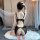 Woman wearing black lace temptation sleepwear set with sheer mesh and open-crotch design, kneeling on white rug in romantic s...