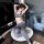 Woman in gray sports bra and open-crotch yoga pants posing on a round table, showcasing the lairuru factory direct sexy sport...