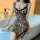 Woman wearing leopard print lace chemise set, seductive erotic sleepwear with black trim and bow straps, posing by bathtub.