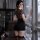 A woman stands by a window wearing a leopard print top with a black mini skirt, paired with lace stockings, showcasing a luxu...