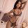 Woman modeling leopard print lingerie set with strappy bra and thong, sheer robe, and cat ears in romantic bedroom setting.