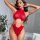 Woman wearing red leopard print bikini set with cutout details and chain accents in a stylish bedroom setting.