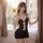 Woman wearing a black halter neck bodycon mini dress with cut-out details, standing by a sunlit window.