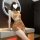 Woman wearing sheer vintage cut-out cheongsam sleepwear set with gold accents, posing on vanity in modern bathroom.