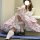 A person wearing a lolita-style dress with a voluminous crinoline skirt, lace stockings, and black shoes, sitting on a blue s...
