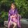 A woman wears a purple lolita dress anime cosplay outfit, featuring a japanese cherry blossom kimono style maid costume with ...
